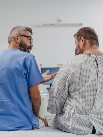 Supportive male physician talking to overweight man in examination room